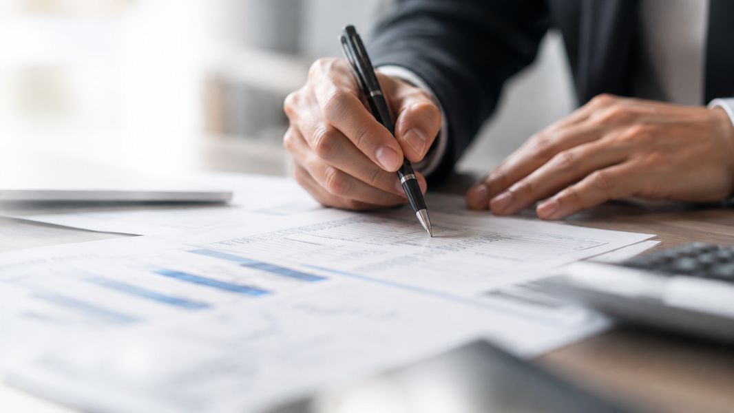 Hände mit Stift über Finanzunterlagen
